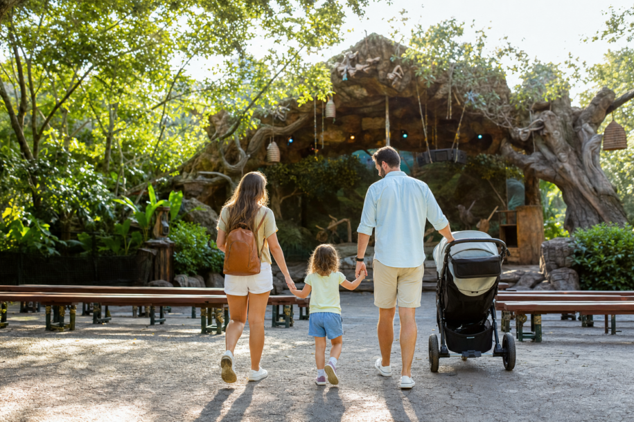 Young family entering a lush tree-themed theater area at a wildlife-inspired theme park on a sunny Orlando day